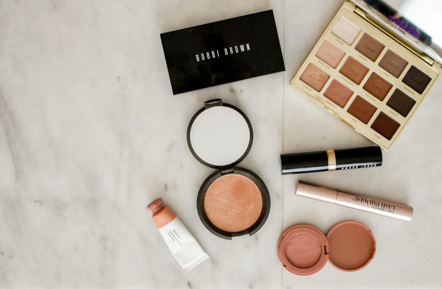 Makeup products arranged on a white marble surface.