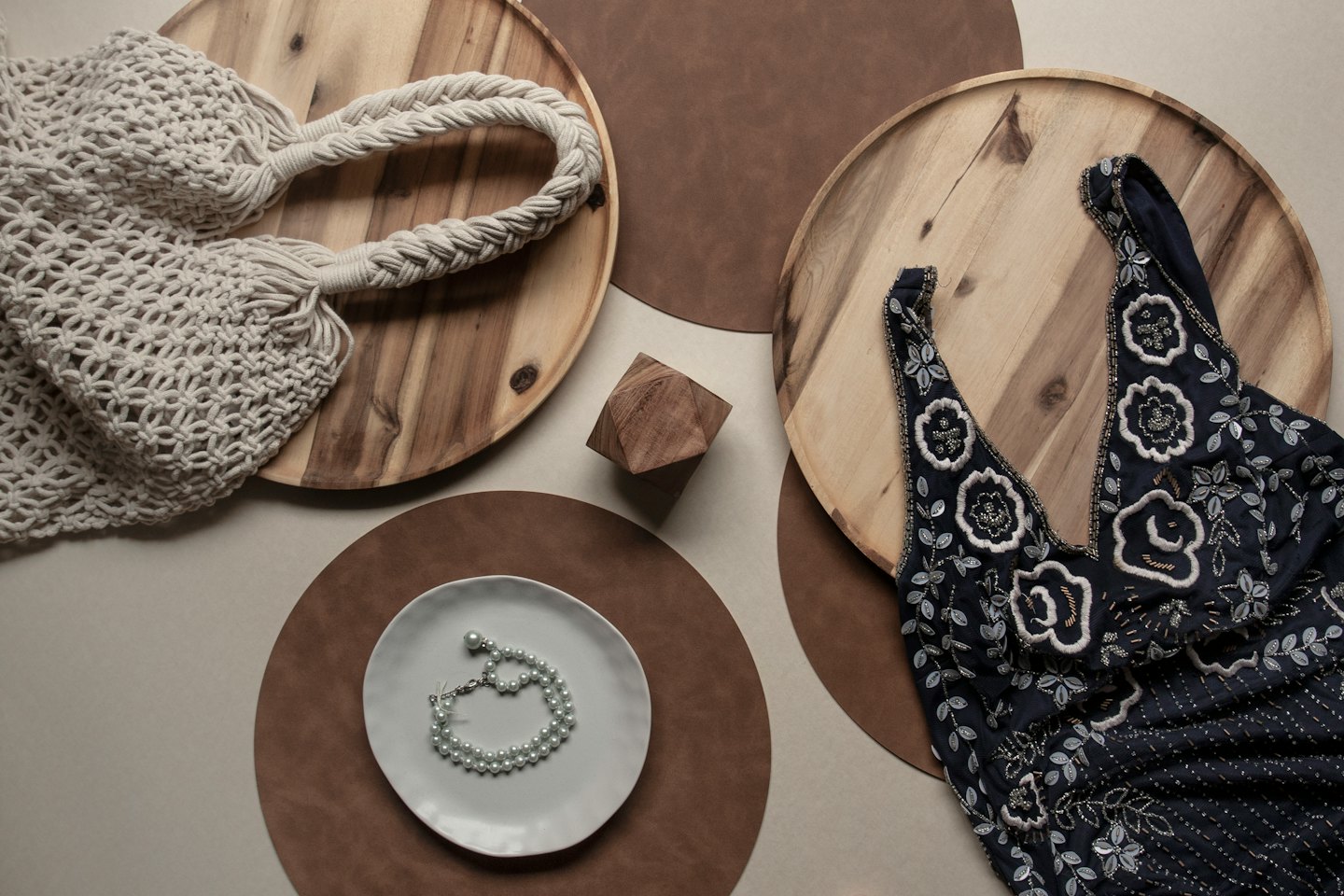 Macrame tote, embroidered dress, and pearls displayed on a tabletop.