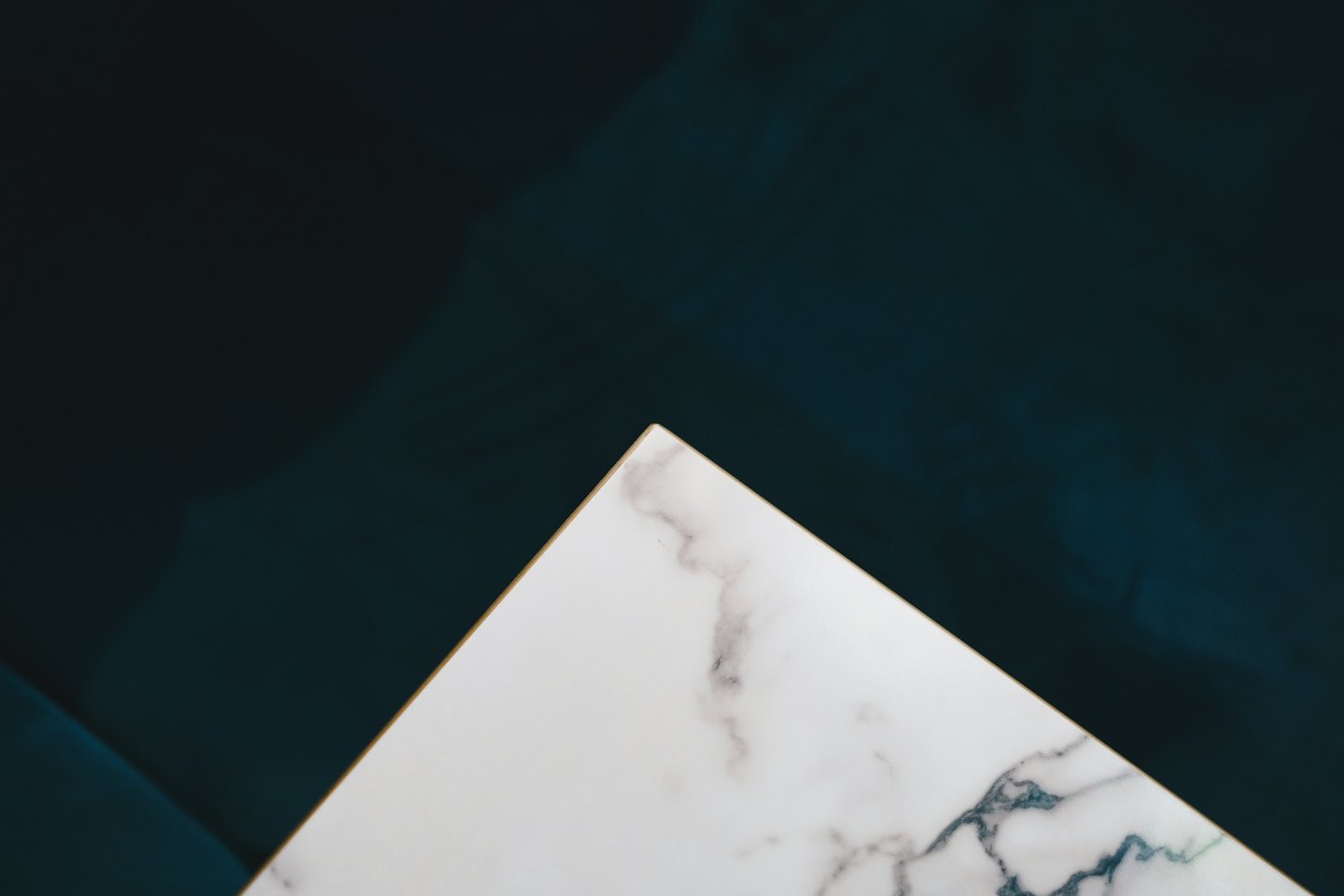 White marble with grey and blue veining on dark teal background.