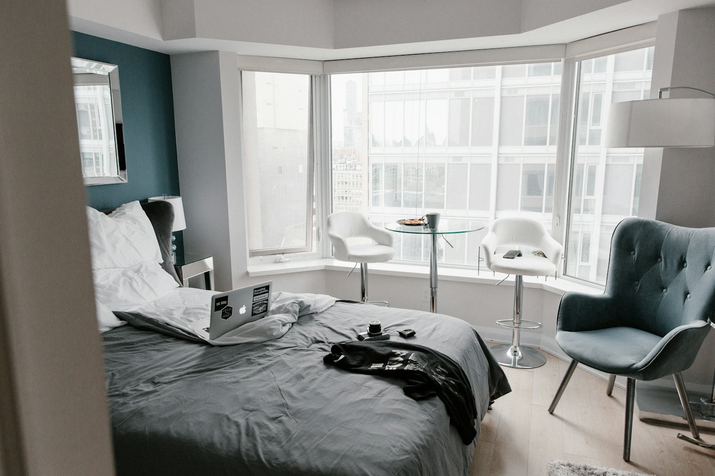 Modern studio apartment with bed, laptop, and city view.