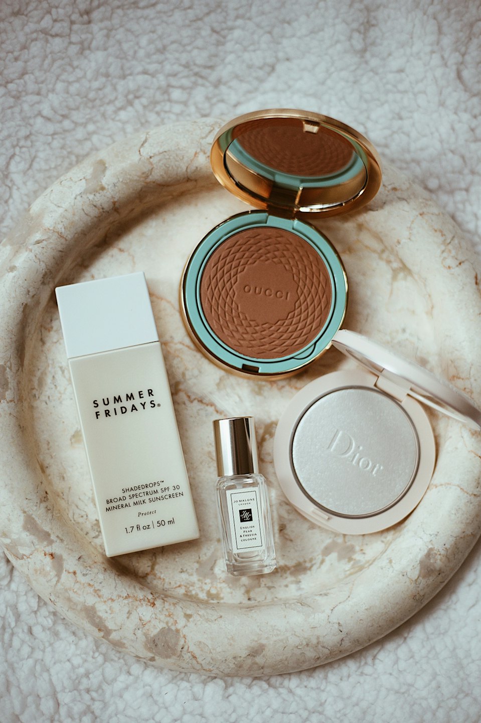 Beauty and skincare products arranged on a marble tray.