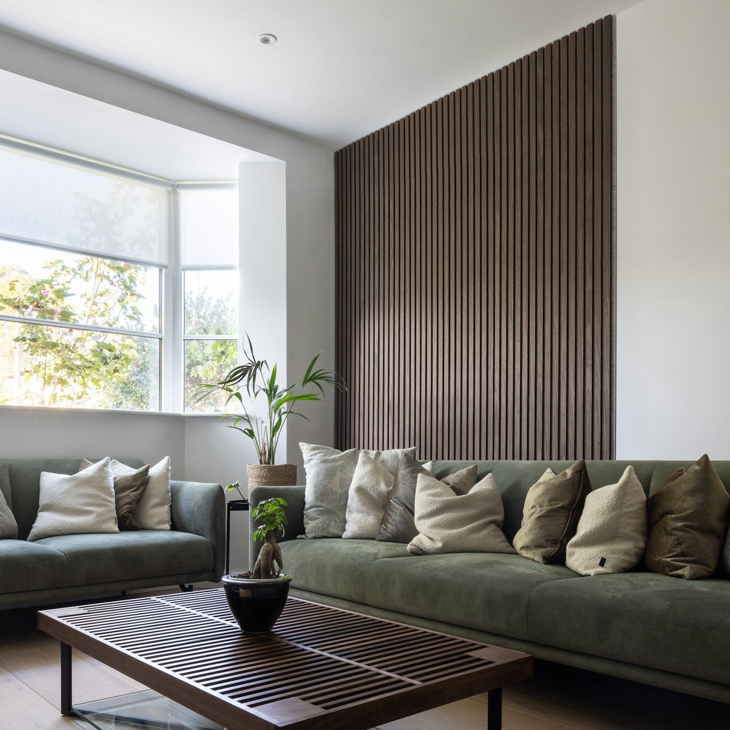 Modern living room with green velvet sofas and wooden coffee table.