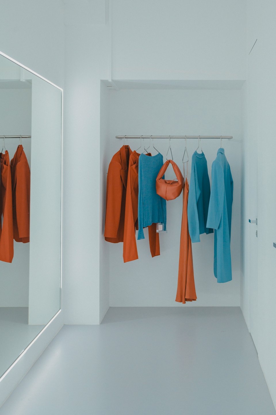 Contemporary clothes rack with blue and terracotta garments.