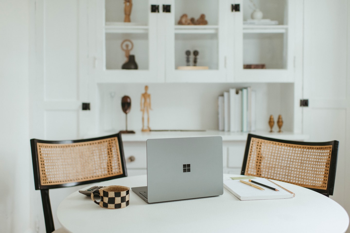 Laptop and office supplies on a round table between chairs.
